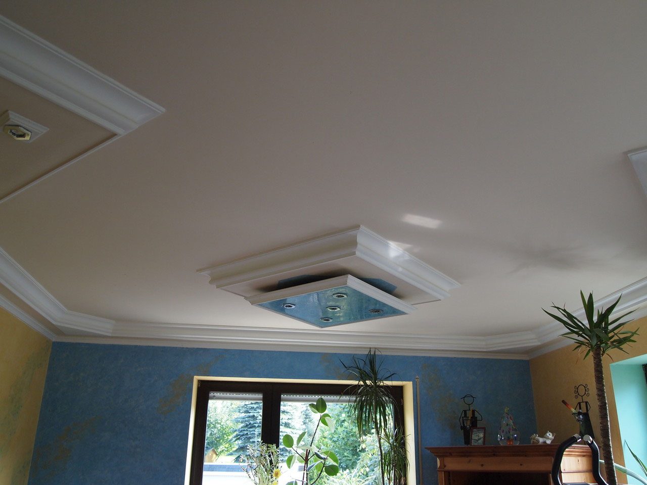 Wohnzimmerdecke mit Stuckgesims und eingelassenem Lichtfeld