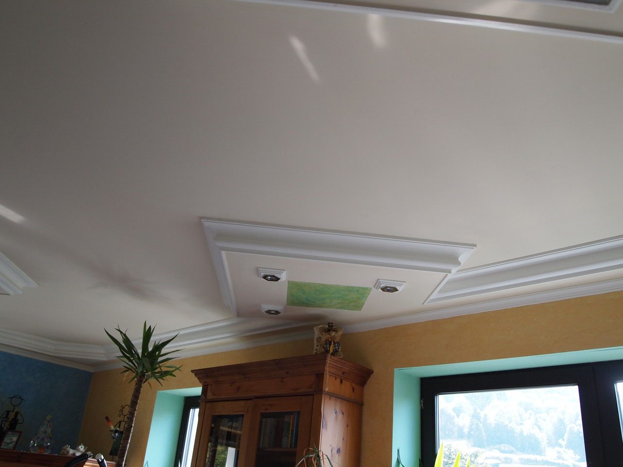 Wohnzimmer mit Stuckdecke, Lichtfeld und blau verputzter Wand